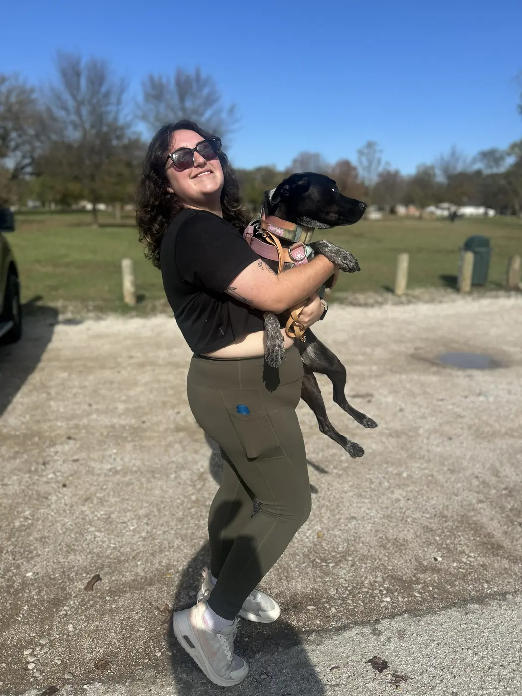 Kourtenay carrying a client's dog at a Houston park